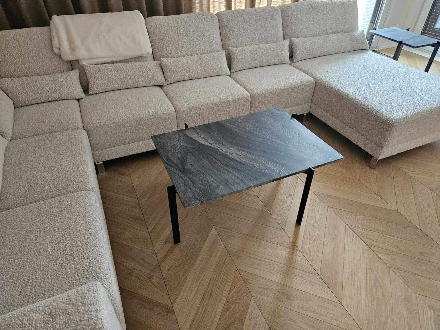Glazowany stolik kawowy z czarnego marmuru na czarnych nóżkach w nowoczesnym salonie.