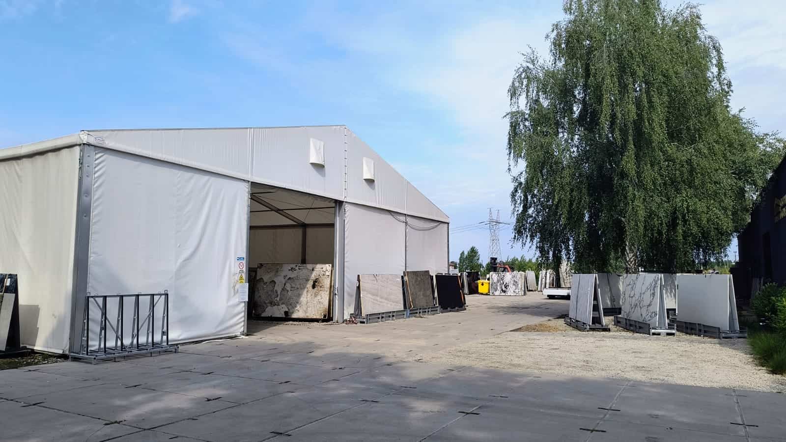 Nowy plac Płyta kamienna na placu firmy Global Stone, magazyn materiałów naturalnych, granitowe i marmurowe bloki, zadaszona przestrzeń wystawowa, logistyka i sprzedaż kamieni naturalnych, nowoczesny zakład kamieniarski.