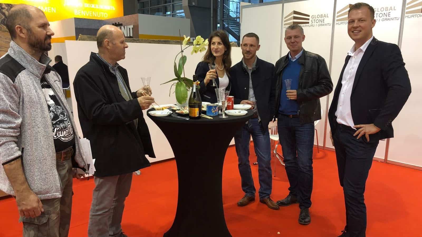 Targi kiedyś Głęboka prezentacja wystawy Global Stone podczas wydarzenia branżowego w Polsce, z grupą profesjonalistów degustujących napoje przy stoisku z eleganckim wysokim stoiskiem.